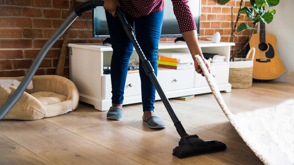woman is cleaning room in vacuum cleaner.
