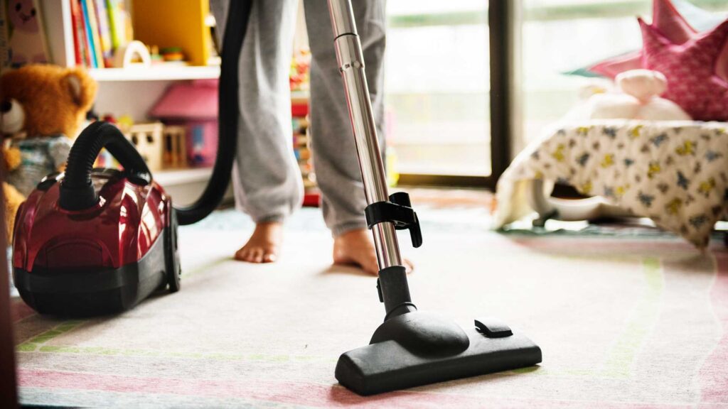 woman cleaning room with vacuum cleaner.