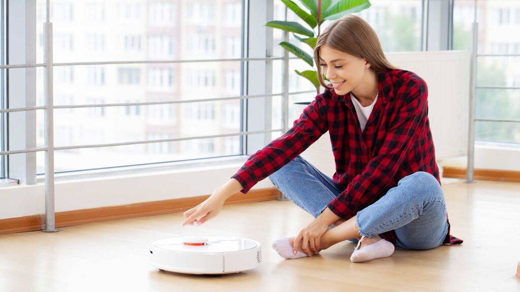 Woman enjoys the work of a smart robot vacuum cleaner.