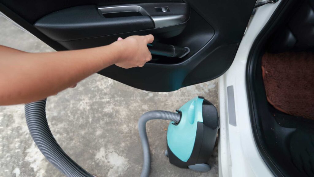 Woman hands using vacuum cleaner interior car.