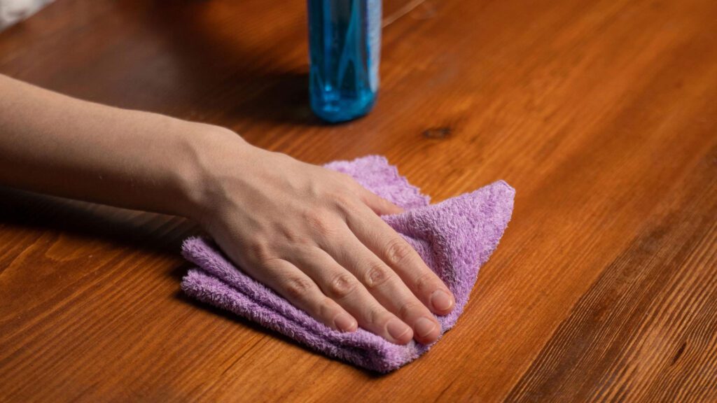 cleaning hardwood table with damp towel