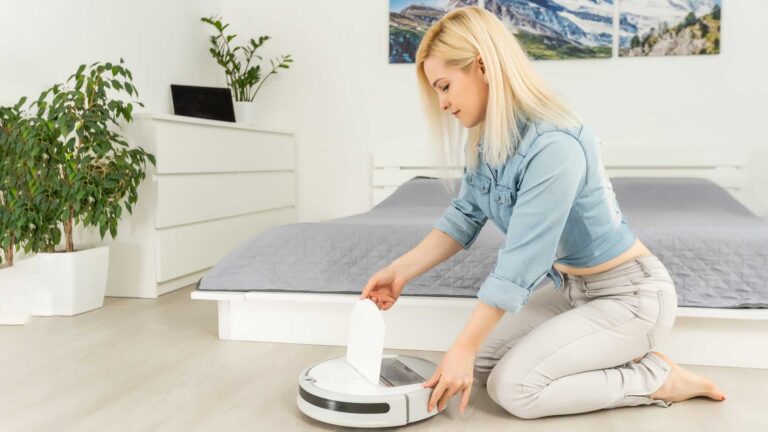 woman turns on smart robot vacuum cleaner.