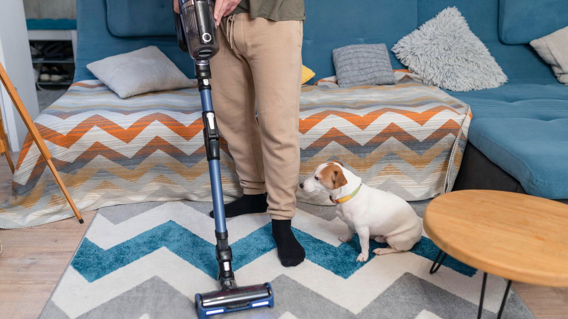 man with dog vacuuming carpet